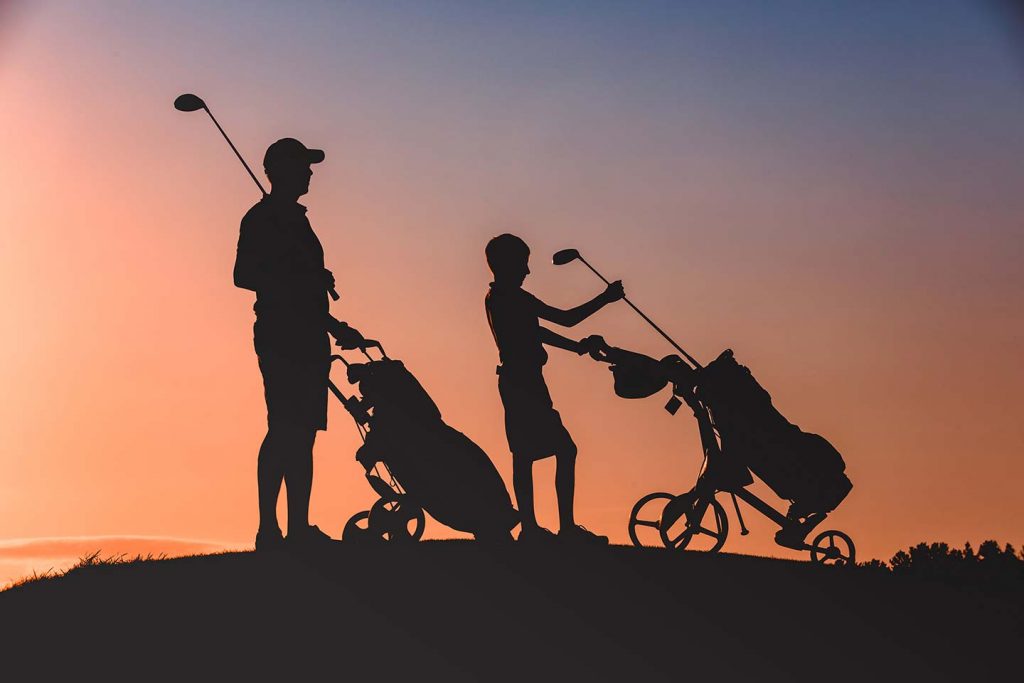 Golf Pro and child silhouetted against the morning sun